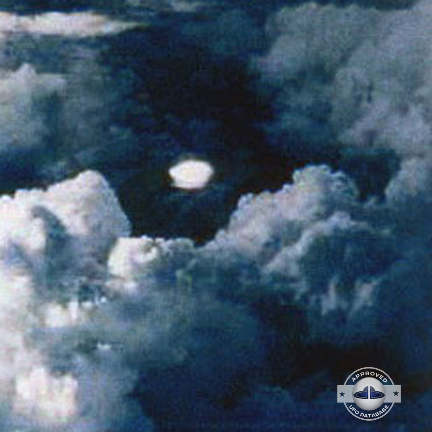 very bright disc-like object remaining stationary near a thunderhead UFO Picture #102-3